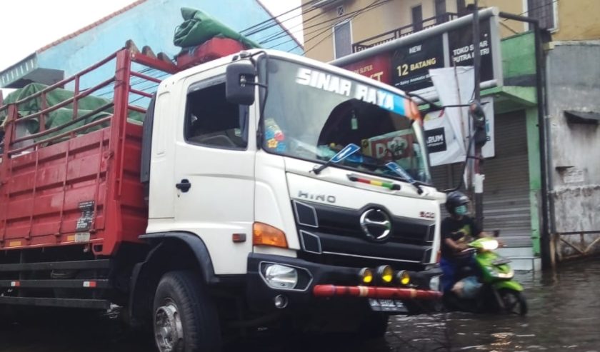 Truk terperosok lubang di depan Pasar Wadung Asri arah Tropodo. Kondisi jalan pagi ini (8/1) masih tergenang