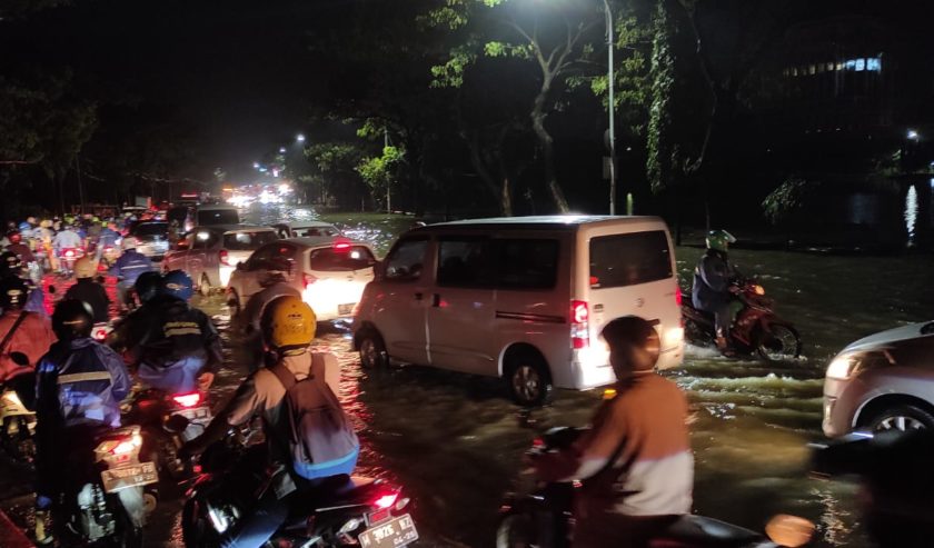 Jalanan di sekitar Waduk Unesa Lidah banjir imbas air di waduk meluap, Senin (21/2) malam. Lalu lintas macet.