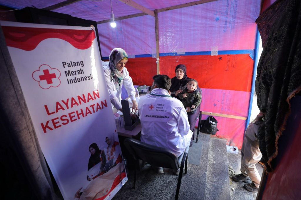 Relawan PMI sedang memberikan layanan kesehatan kepada pengungsi Gaza yang berada di perbatasan Rafah Palestina, Minggu (11/2/2024). Foto: PMI