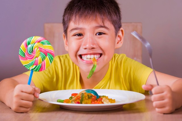 Ilustrasi anak makan permen.