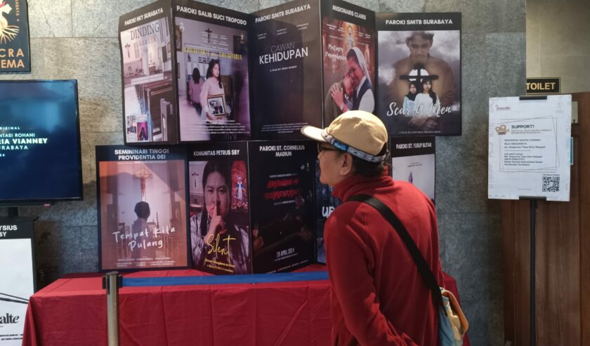 Salah satu pengunjung saat melihat beberapa pameran poster hasil Festival Film Sacra Cinema di Galera Sacra Cinema Gereja Katolik Hati Kudus Yesus (HKY) Katedral Surabaya, Sabtu (11/5/2024). Foto: Risky suarasurabaya.net